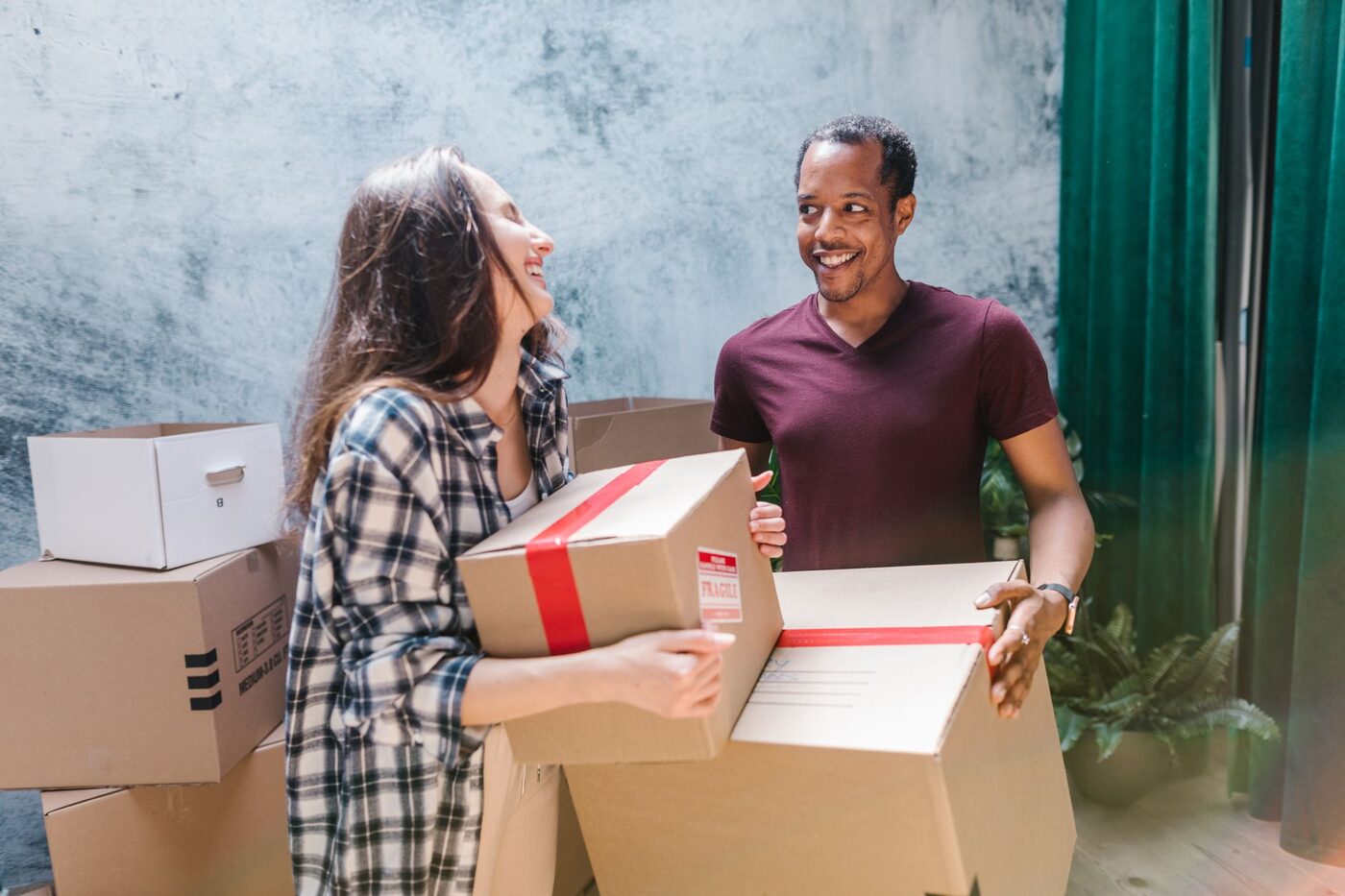 A couple carrying moving boxes into their new home