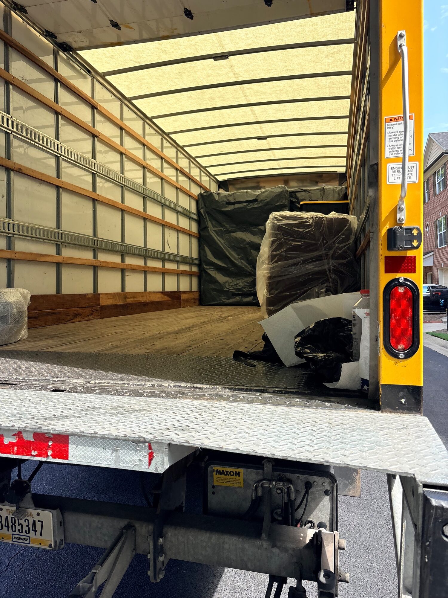 Lift gate raised at the back of a truck with wrapped furniture inside