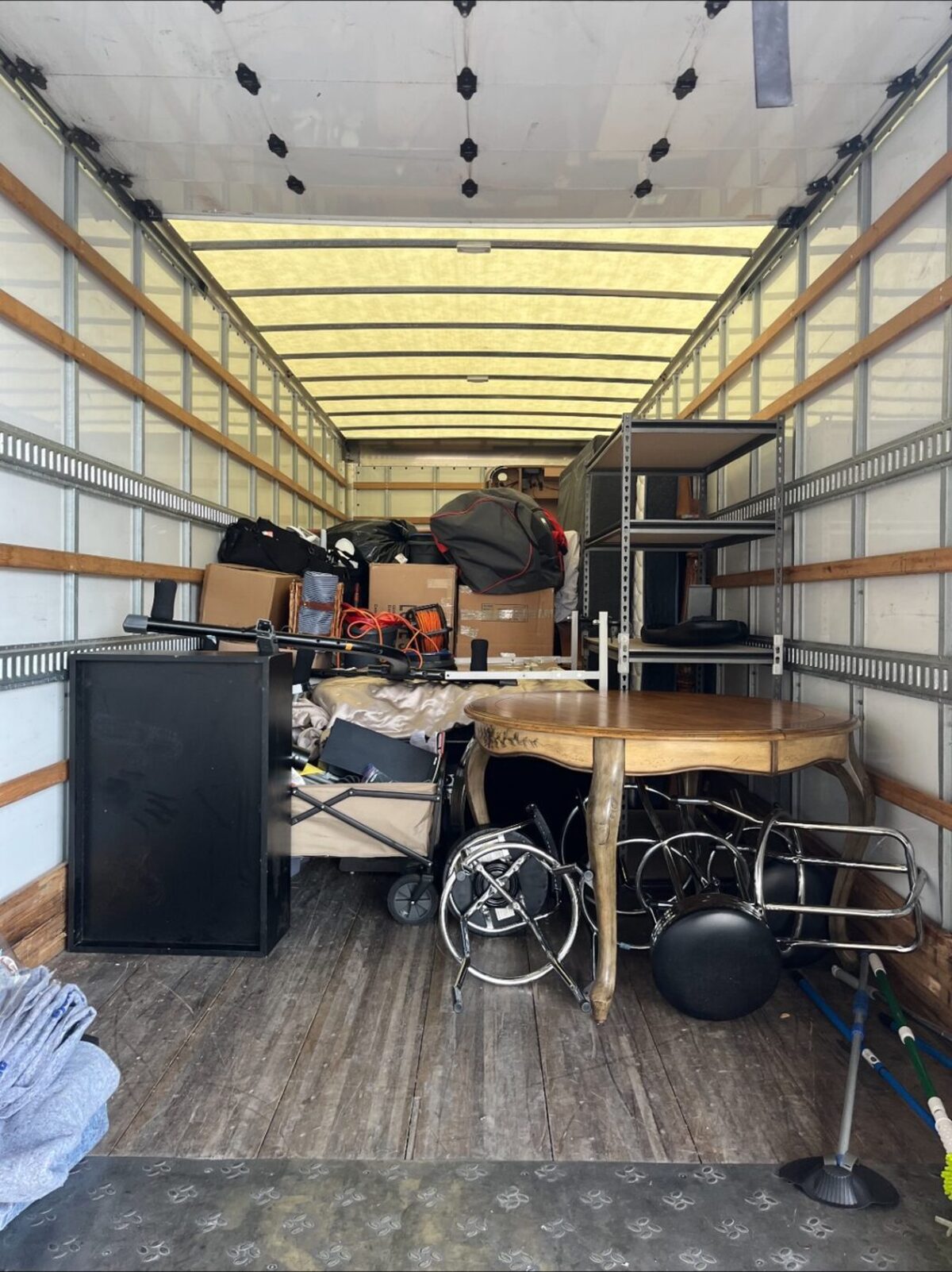 Interior of a loaded box truck with a dining table, shelving and stacked items
